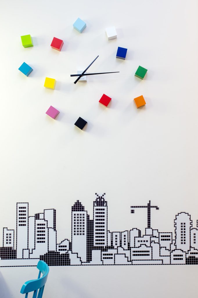 Detail: colourful cube clock above a skyline drawing