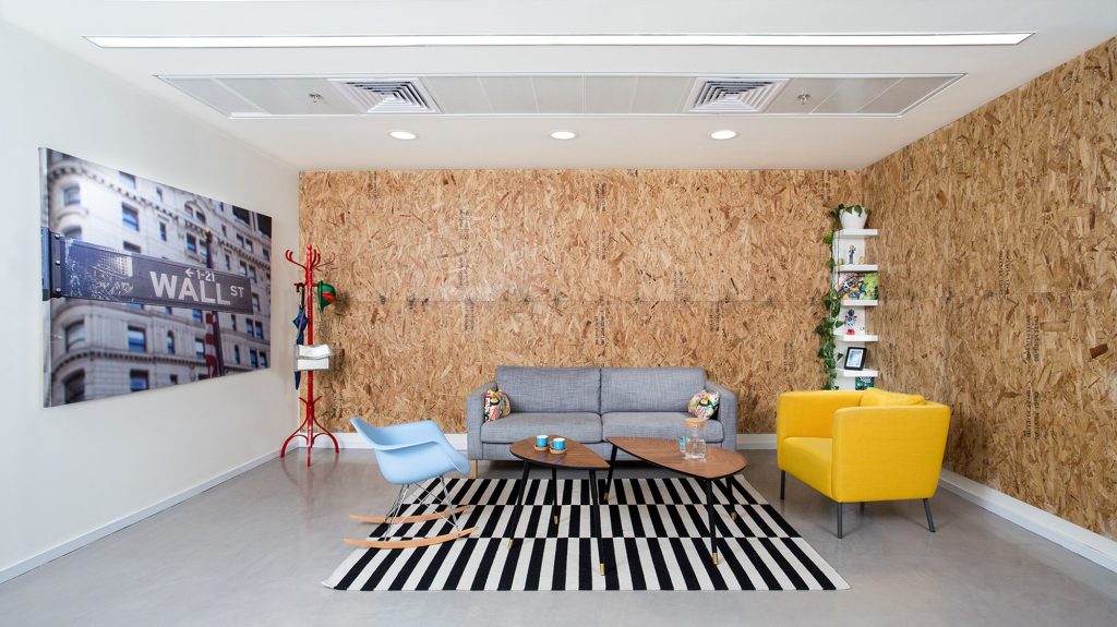 Grey sofa and a yellow armchair against the OSB wall