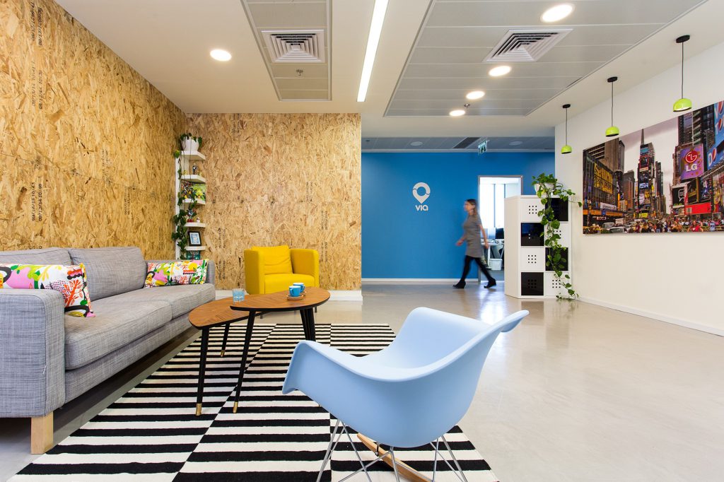 Lounge with an OSB wall, a grey sofa and a striped rug