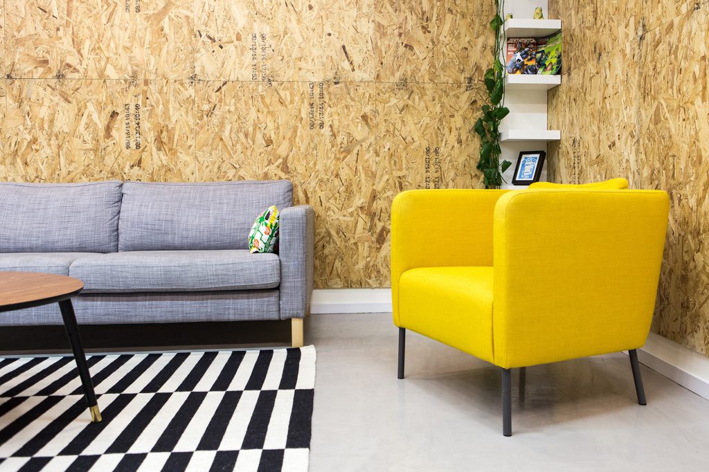 Yellow armchair and a grey sofa on a black-and-white rug