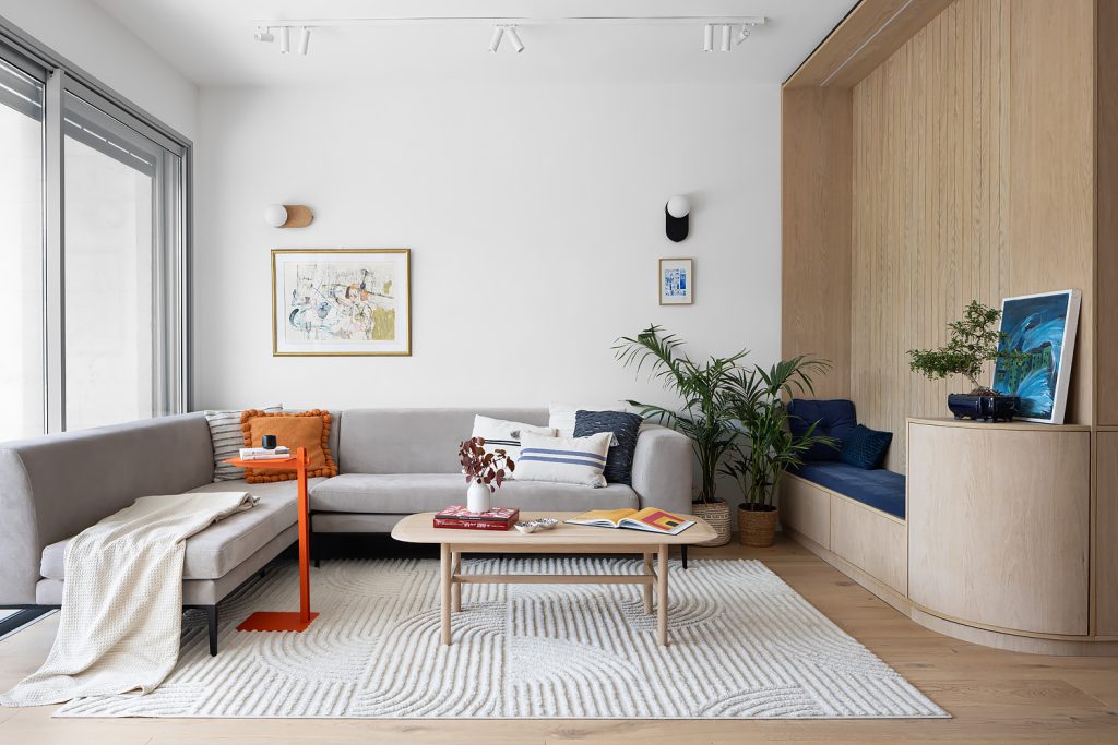 Living room with a grey sofa, an orange side table and a curved wooden bench