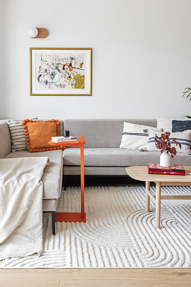 Grey sofa with orange cushions and a textured rug