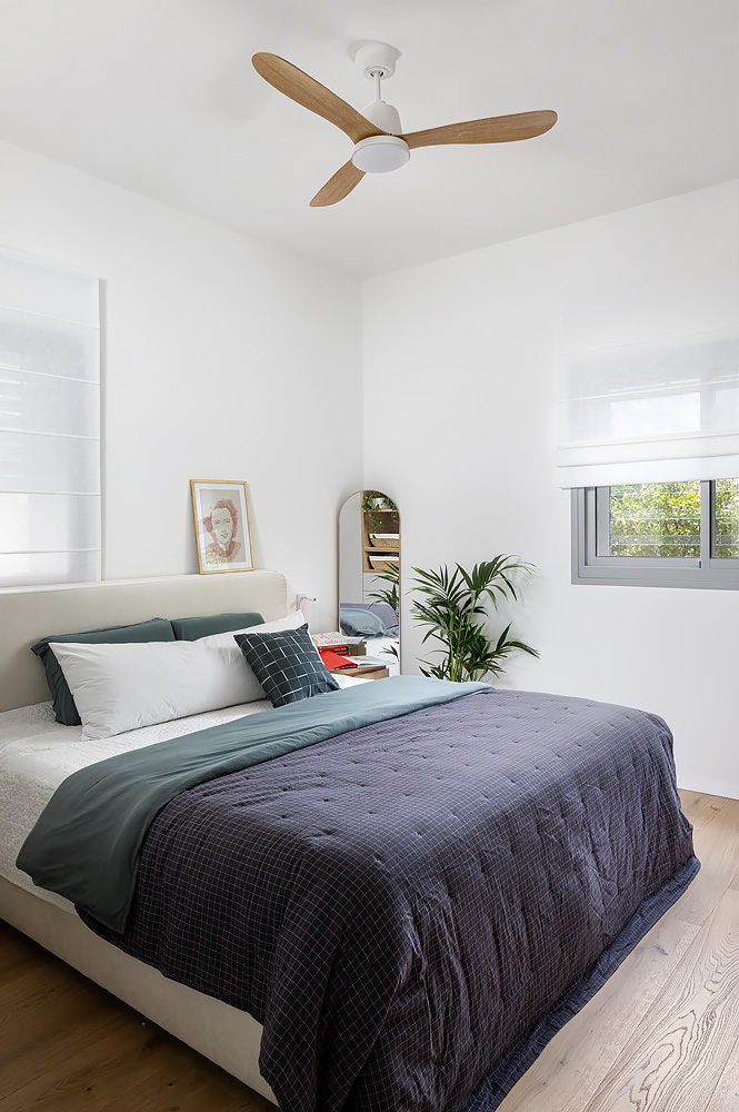 Bedroom with a navy bedspread and a ceiling fan