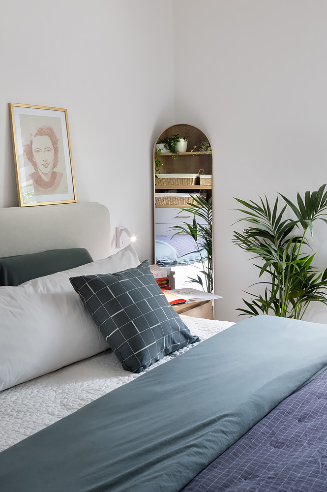 Bed in blue and green linen with an arched mirror