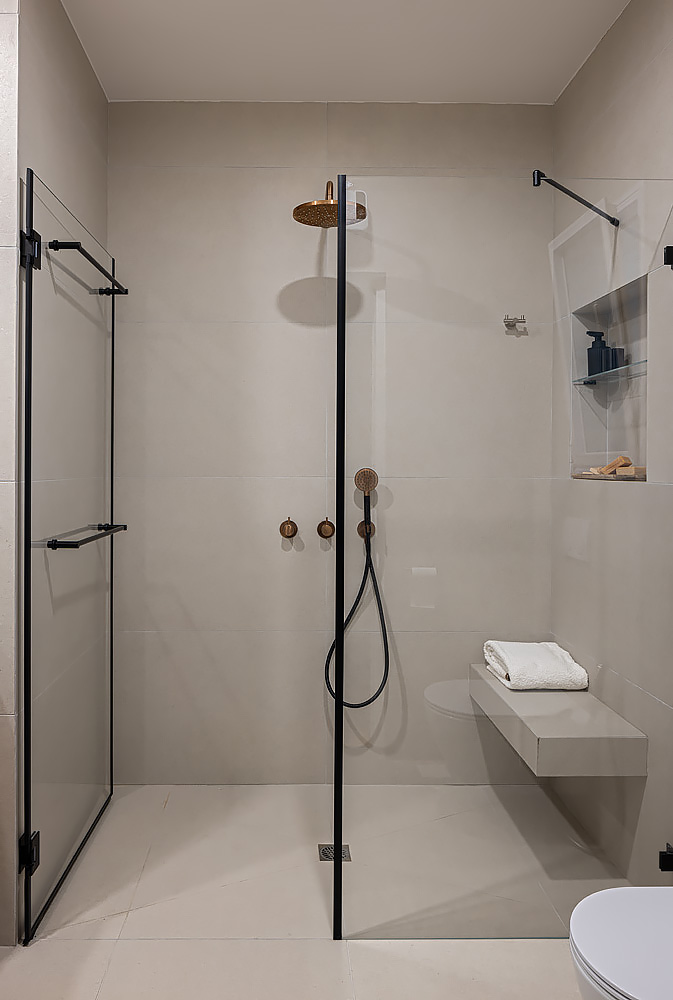 Shower with a black-framed glass screen and a built-in bench