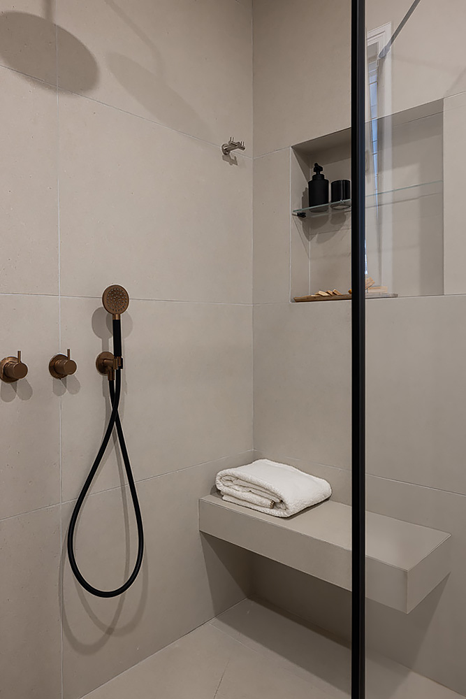 Stone-toned shower with copper-tone taps and a niche