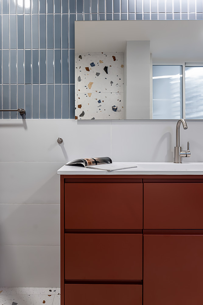 Brick-red vanity below long blue tiles