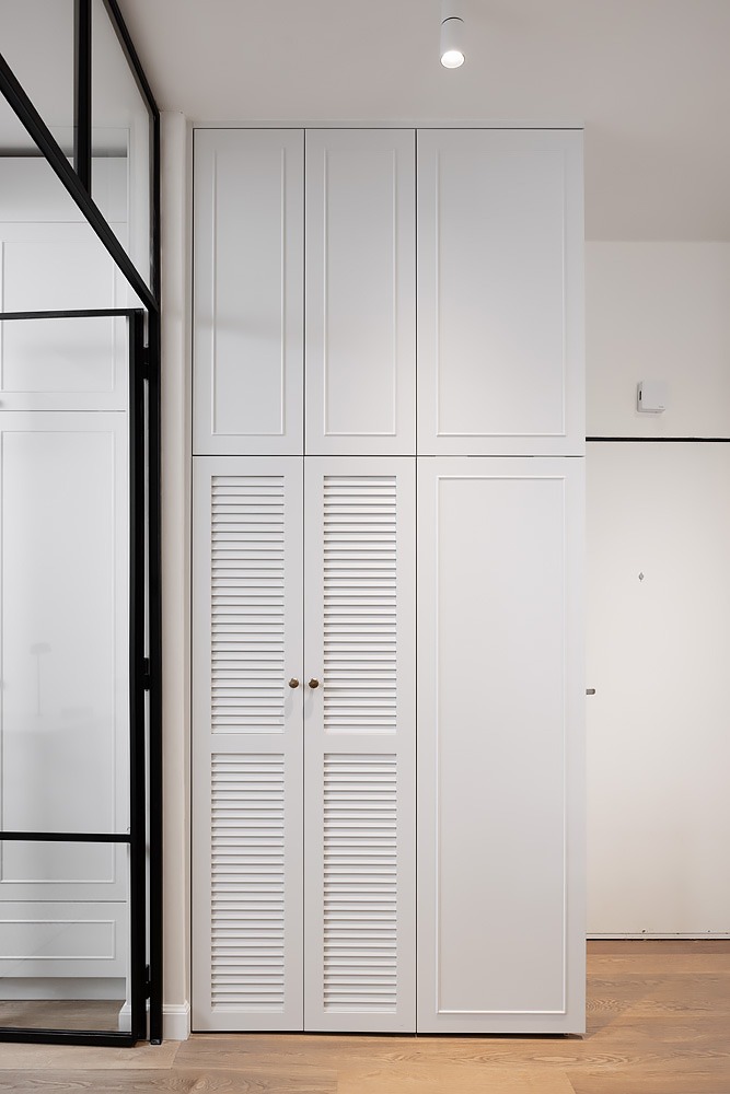 White cupboards with louvred doors in the hallway