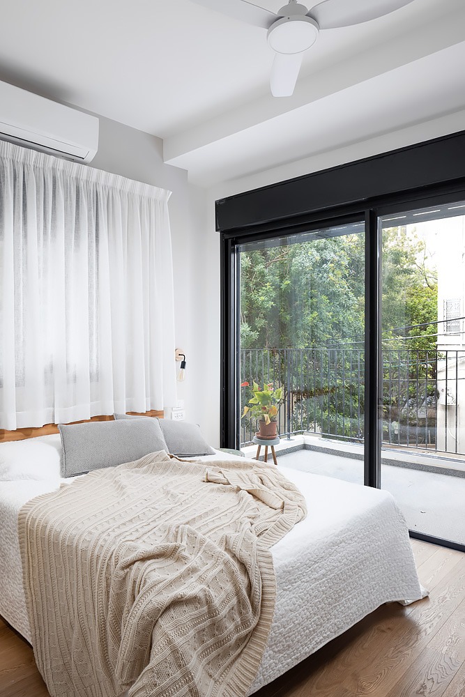 Bedroom with a glass door to the balcony and light bedding