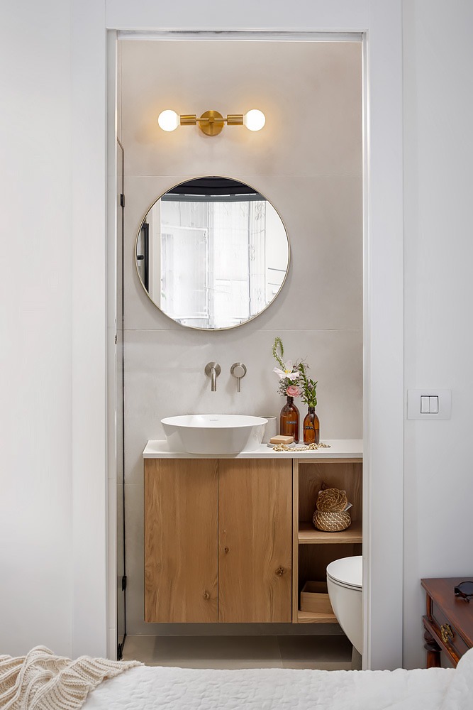 Guest toilet with a small wooden vanity and a brass wall light