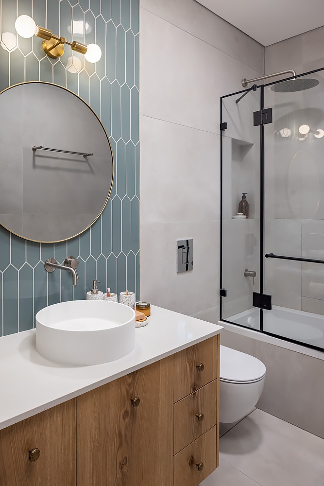 Wooden vanity and round mirror against mint-coloured tiles