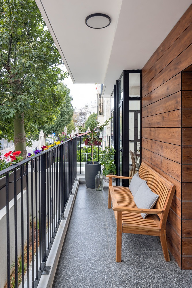 Narrow balcony with a timber-clad wall, a wooden bench and planters, De Haas St. apartment in Tel Aviv – Chen Shadmi, Shadmi Design