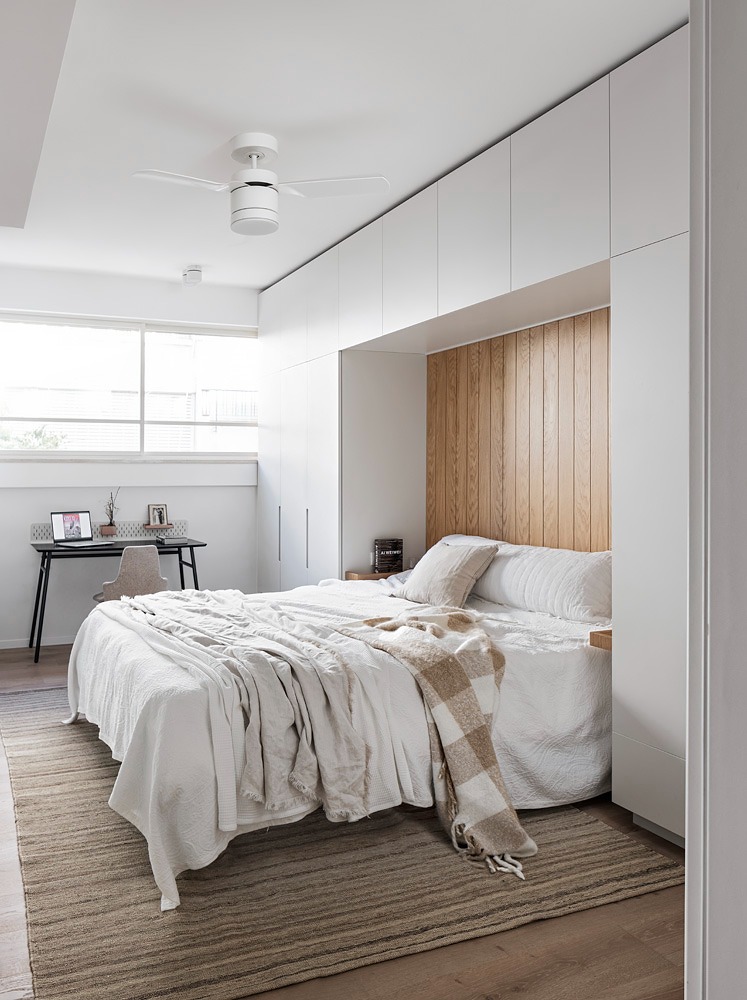 Bedroom with white cabinets around the bed and a woven rug
