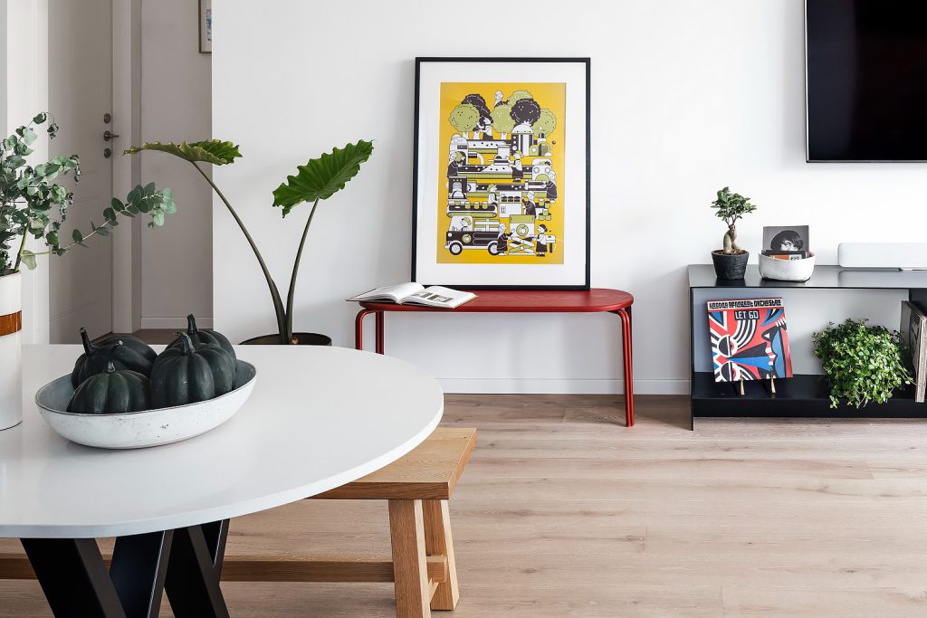 Red console and a yellow artwork beside a round dining table