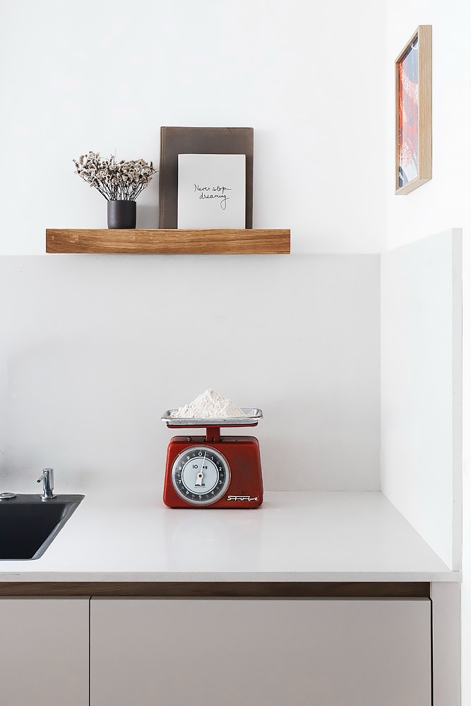 Detail: red scales on a white counter below a wooden shelf
