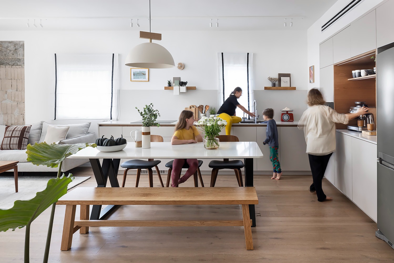 Dining table with black legs facing a white kitchen