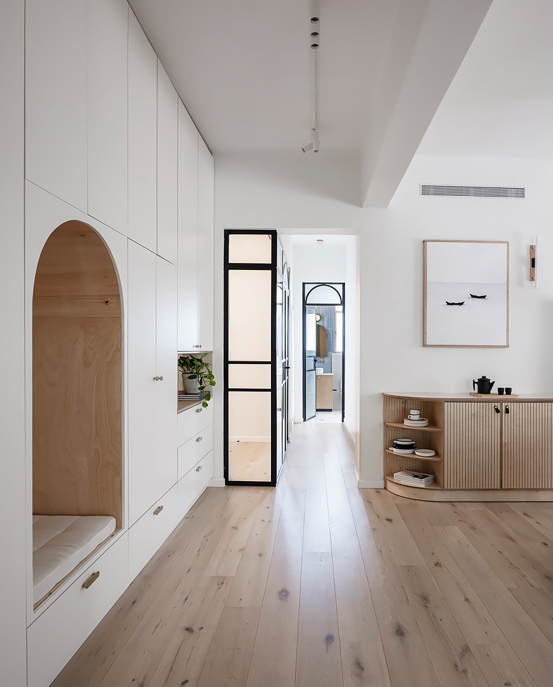 White hallway with an arched niche and a black glass door