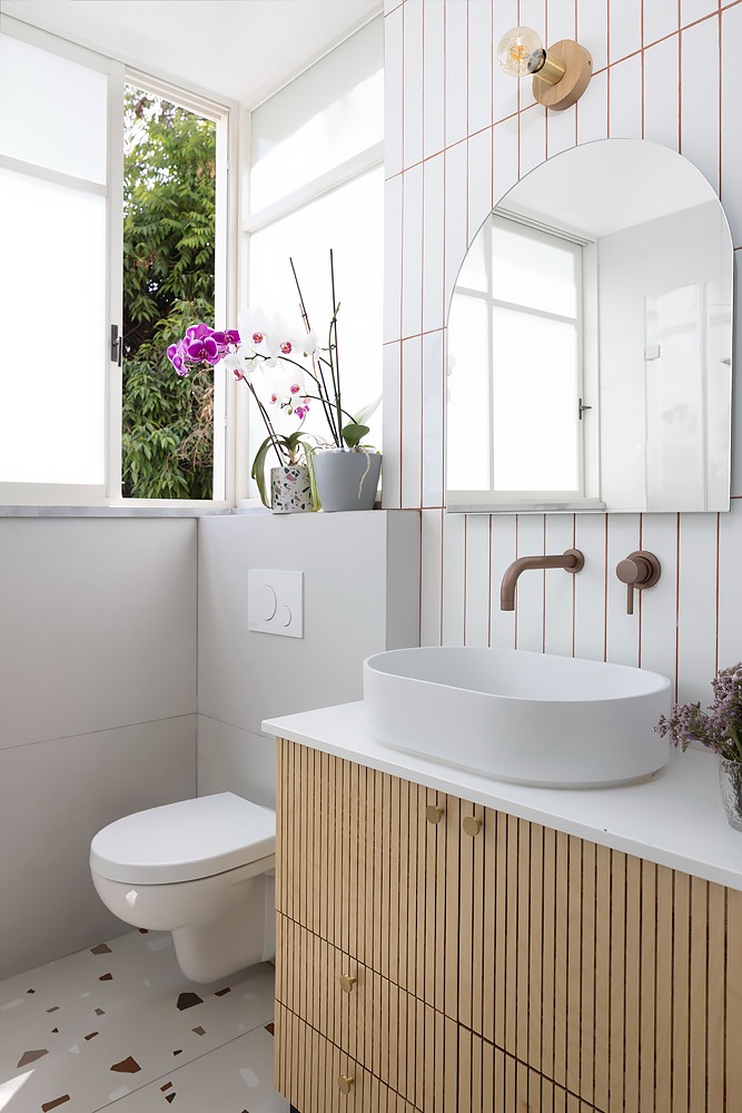 Bowl basin on a fluted wooden vanity with an arched mirror