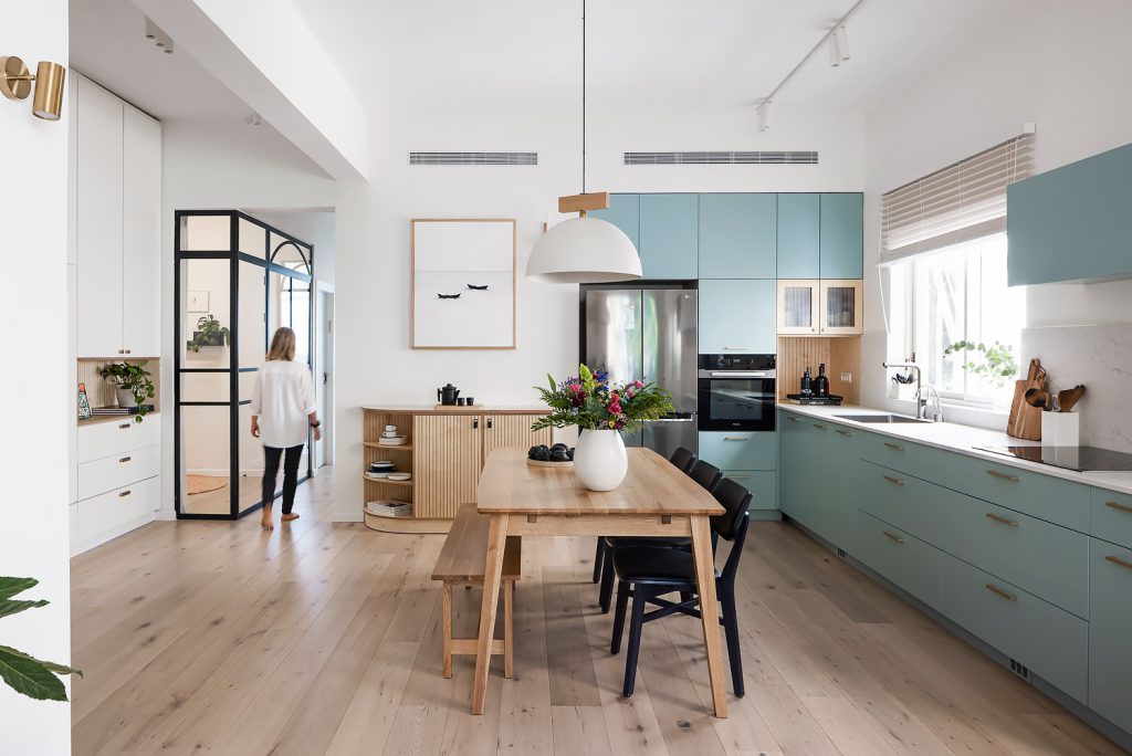 Pale blue kitchen with upper cabinets and a wooden table