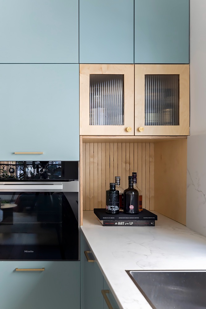 Pale blue cabinets with a wooden, fluted-glass display unit