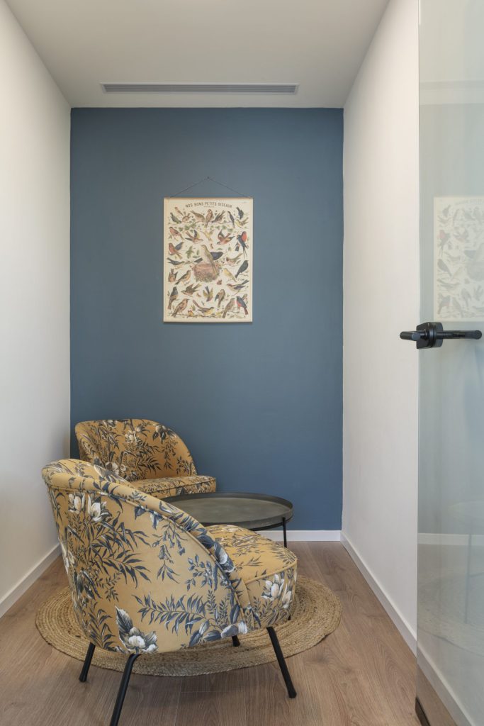 Waiting nook with patterned armchairs against a blue wall