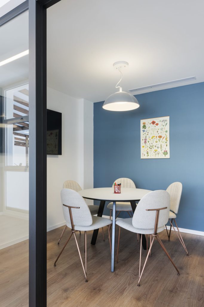 Small meeting room with a round table and a blue wall