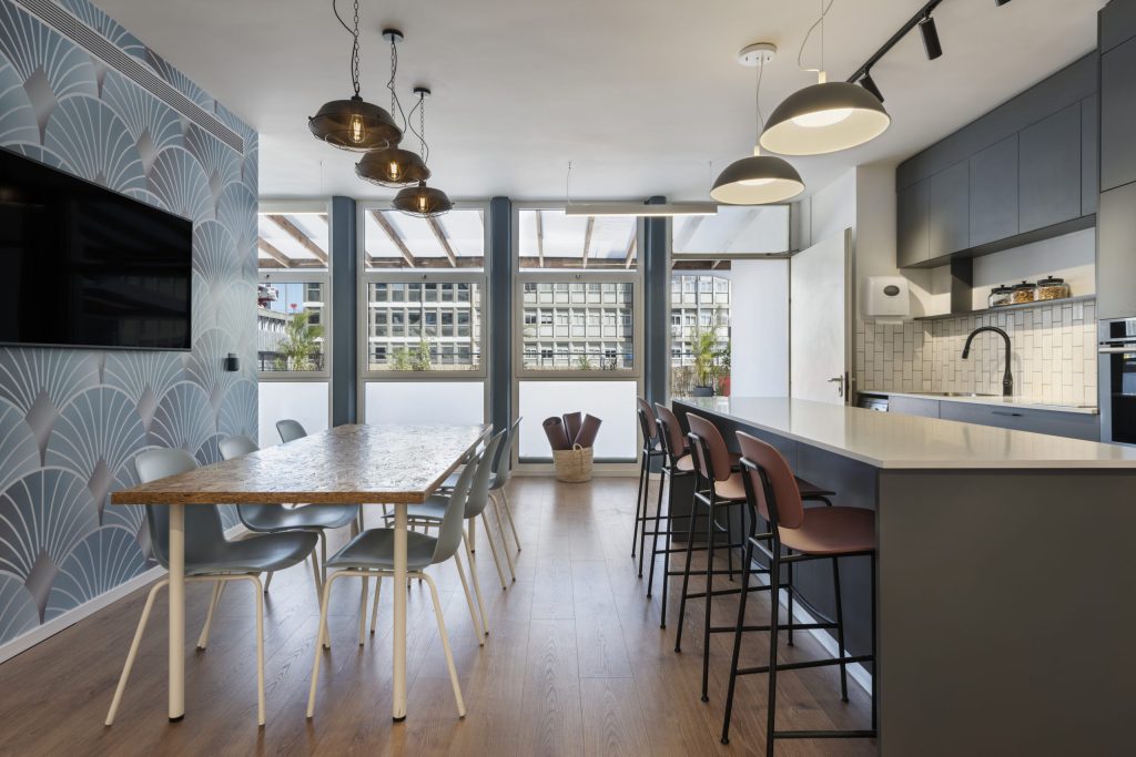 Long table and kitchen bar facing a fan-pattern wallpaper wall