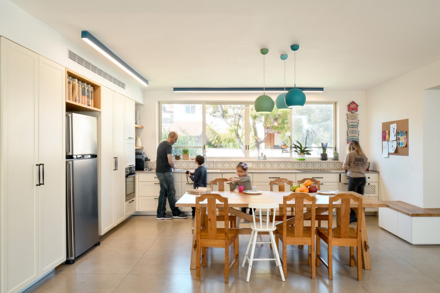 Open kitchen with a wooden dining table and teal pendants