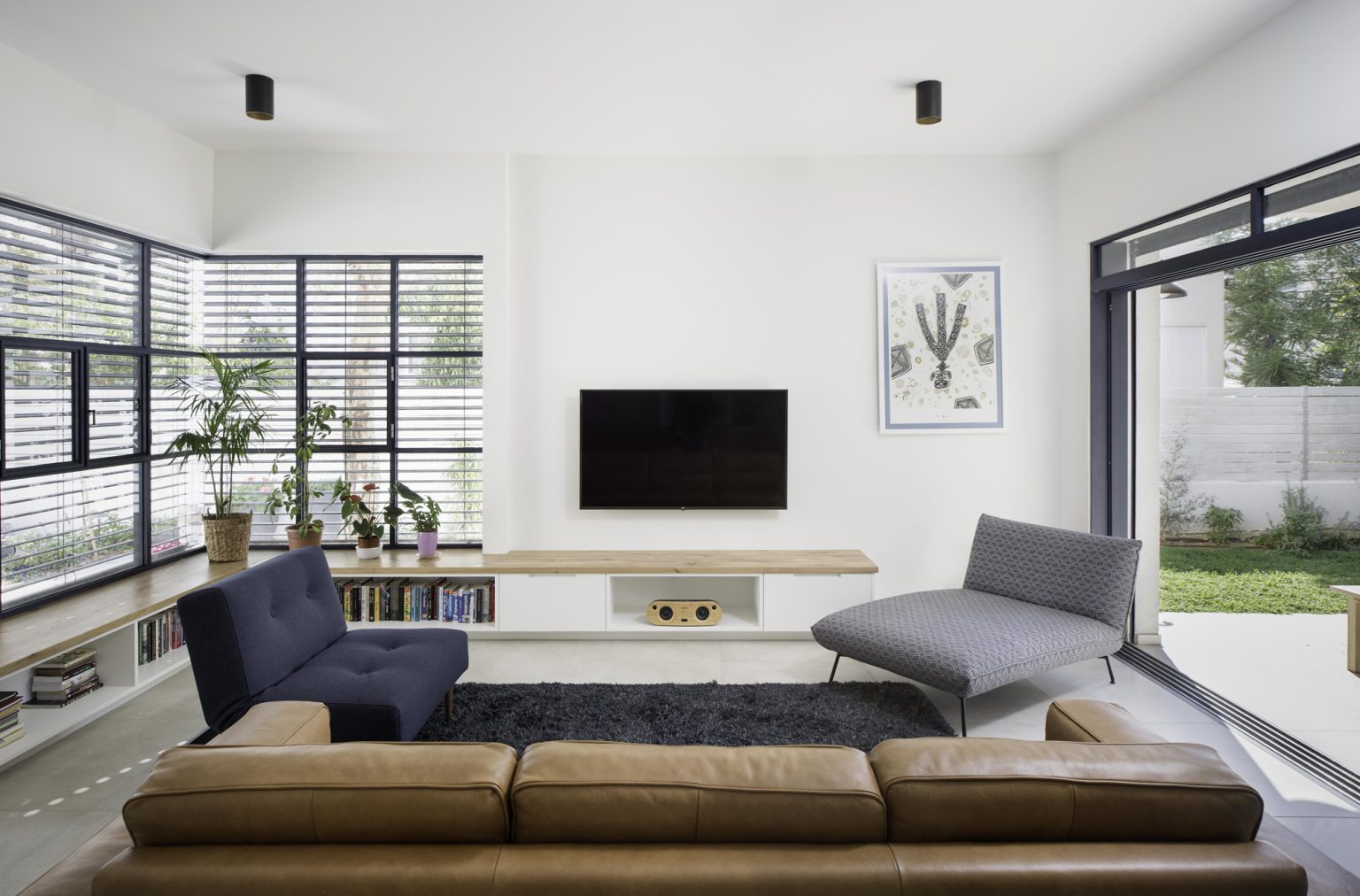 Leather sofa, a black rug and a wooden bench below the TV
