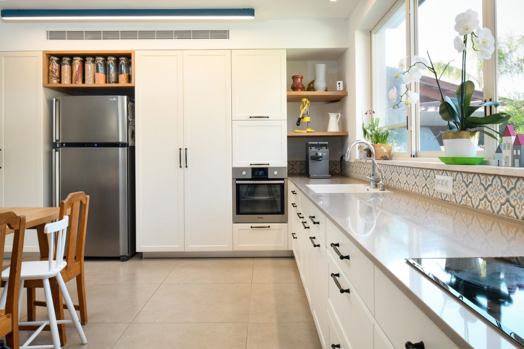 White kitchen with a stainless fridge and open wooden shelves