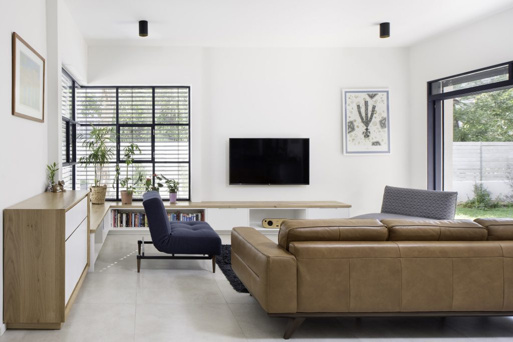 Living room with a tan leather sofa and black-framed garden windows