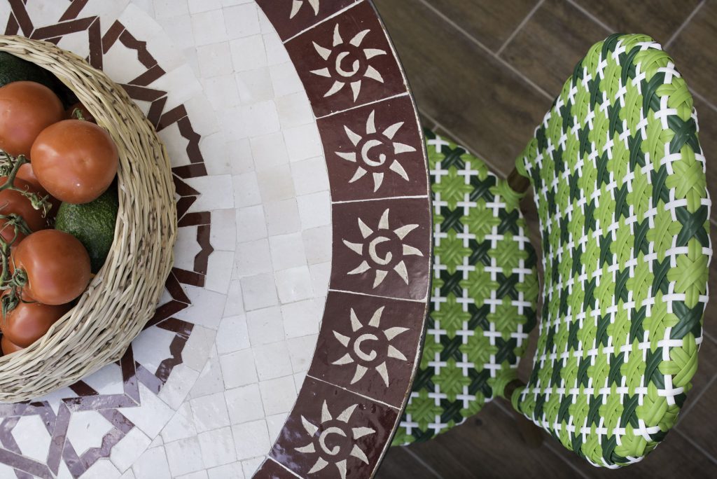Detail: mosaic table and green woven chairs