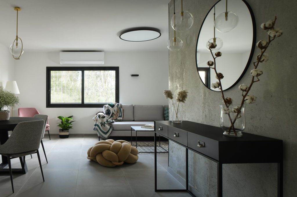 Concrete-plaster wall with an oval mirror and a black console, apartment in Ramat Hasharon – Chen Shadmi, Shadmi Design
