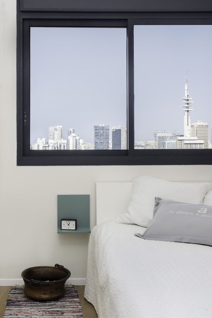 White bedroom facing a window to the city view