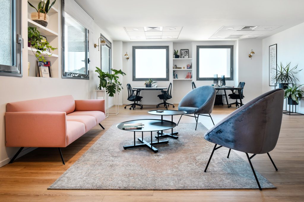 Waiting area with a pink sofa facing workstations