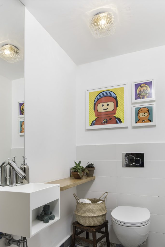 Guest toilet with a white wall-hung basin and colourful prints