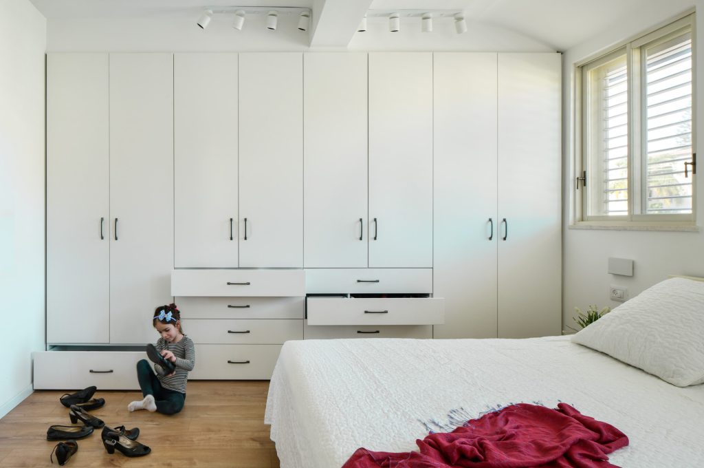 Bedroom with a white wardrobe wall and open drawers