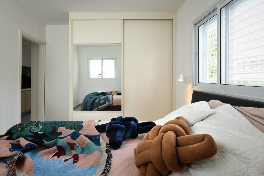 Bed with a colourful throw facing the wardrobe