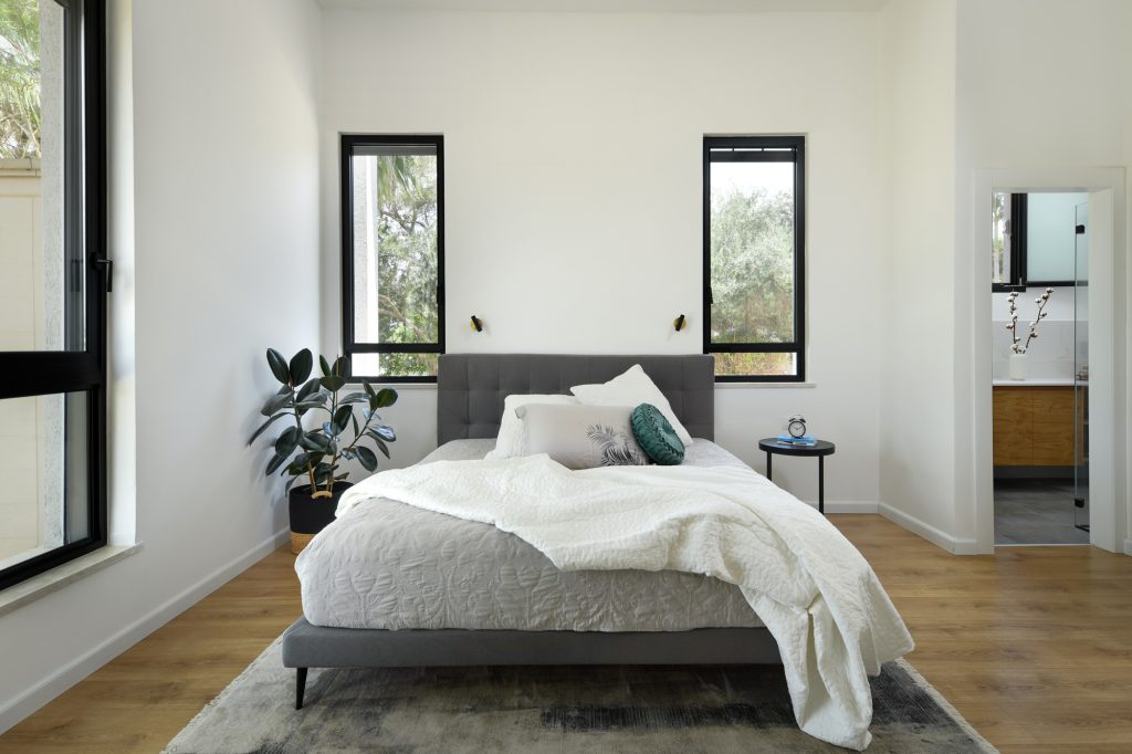 Bedroom with two black windows above the bed