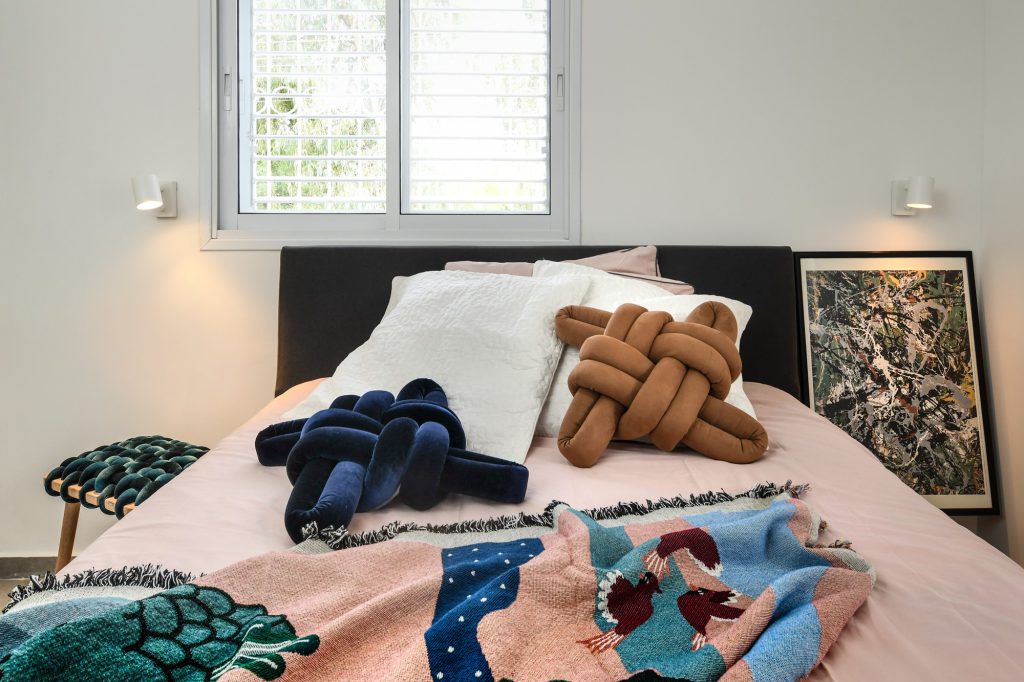 Bed with pink linen and knot cushions