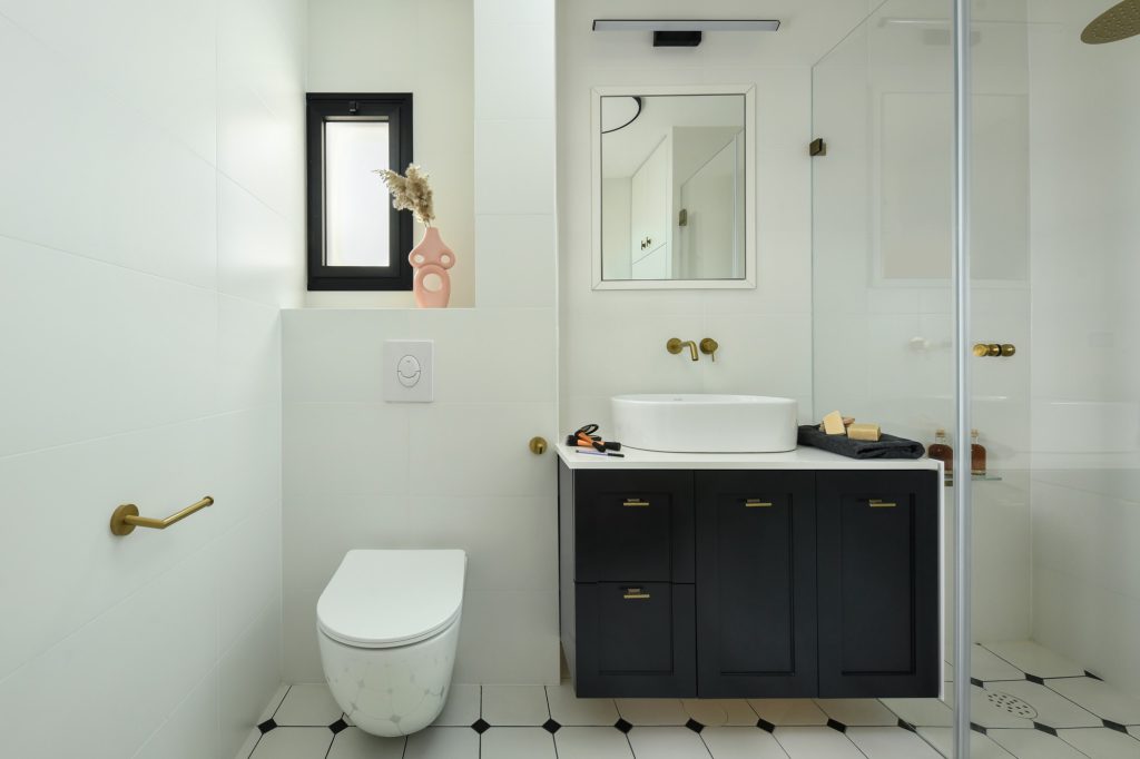 Bathroom with a black vanity, brass taps and a dotted floor
