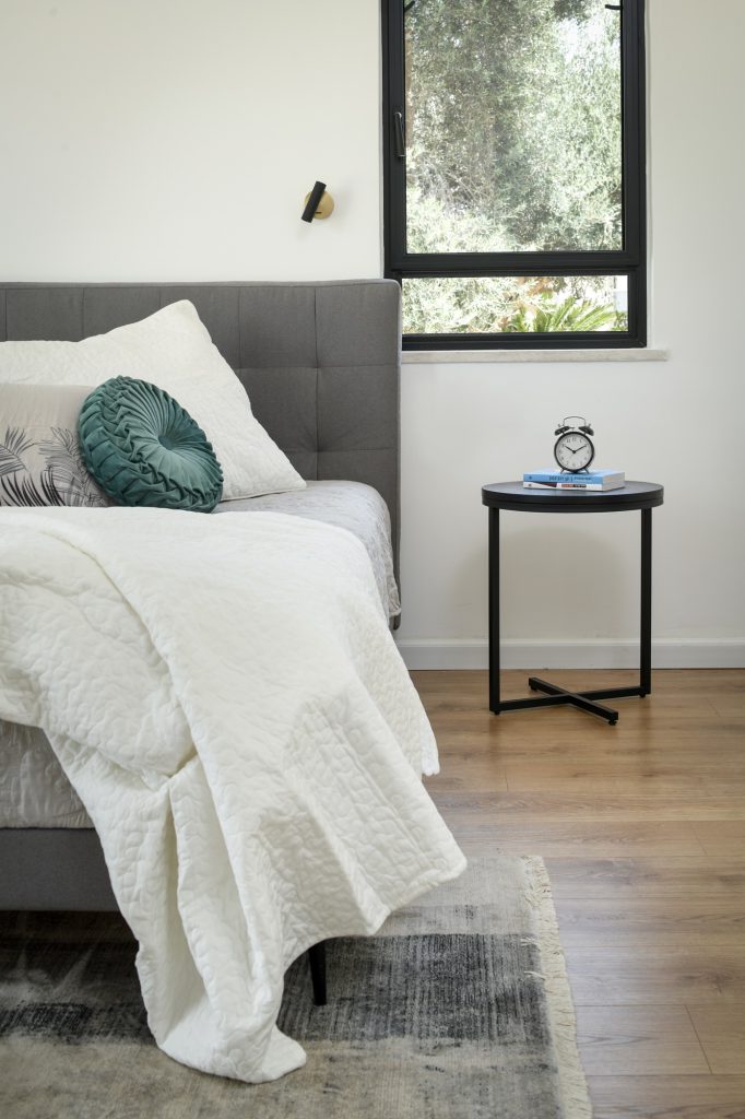 Bed with a grey headboard and a round nightstand