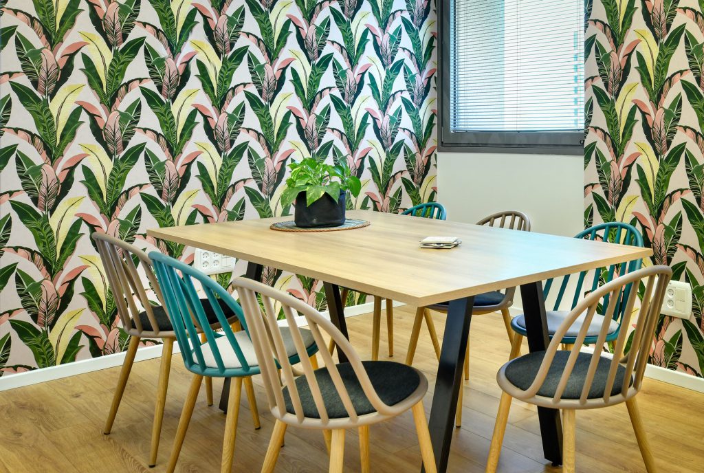 Meeting room with pink-and-green leaf wallpaper and a wooden table