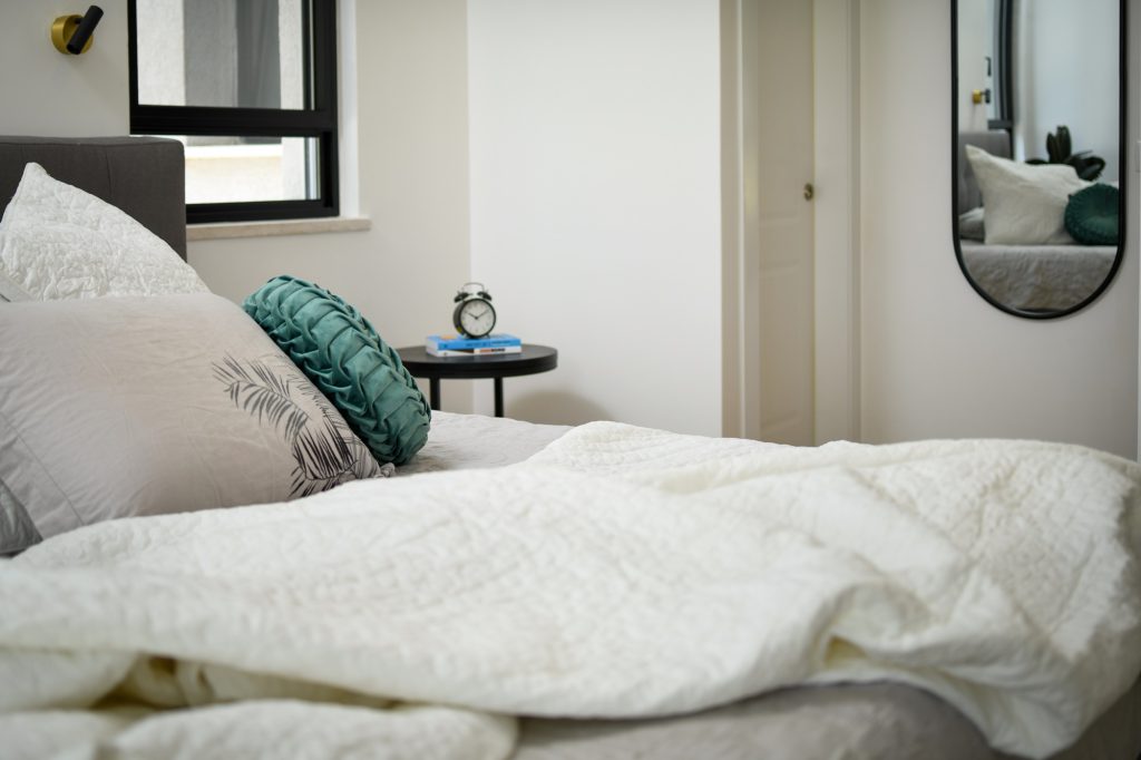 Detail: white bedding and a teal cushion