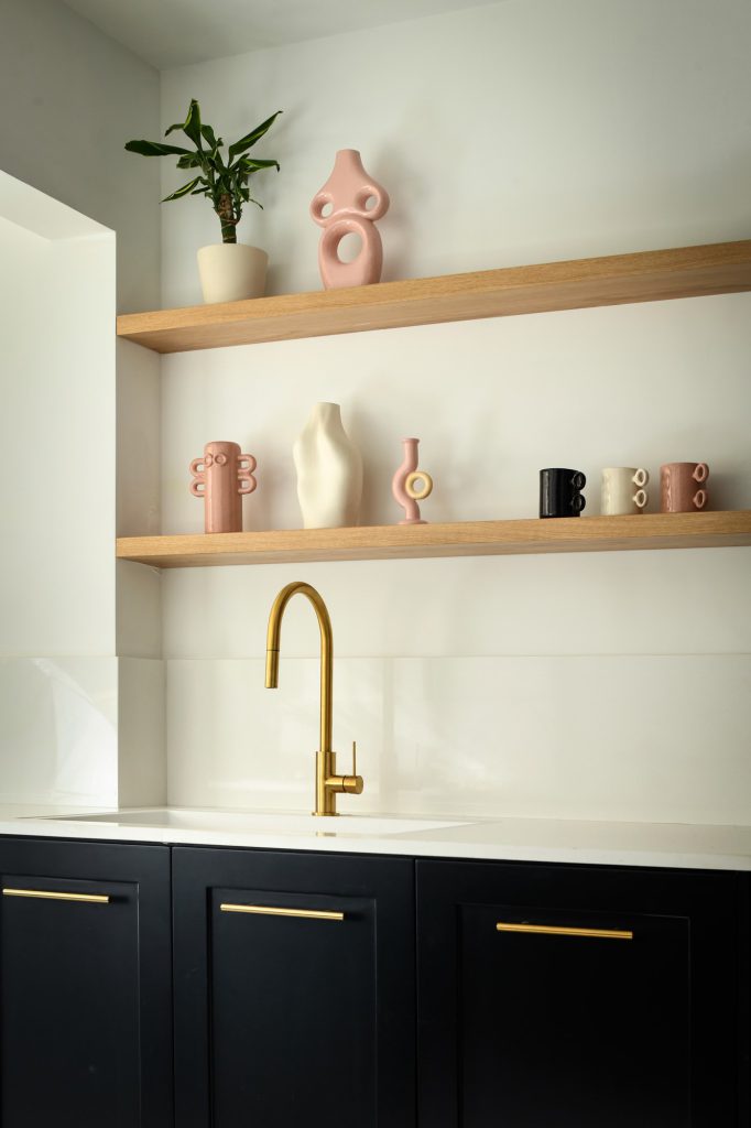 Wooden shelves with pink ceramics above the sink