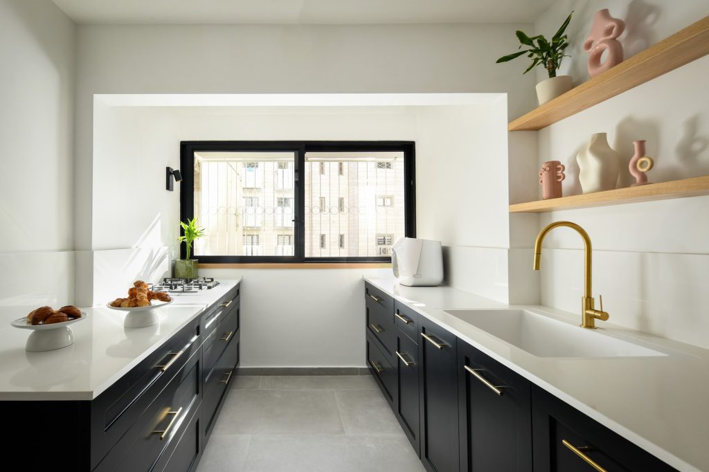 Black kitchen with open wooden shelves and a brass tap