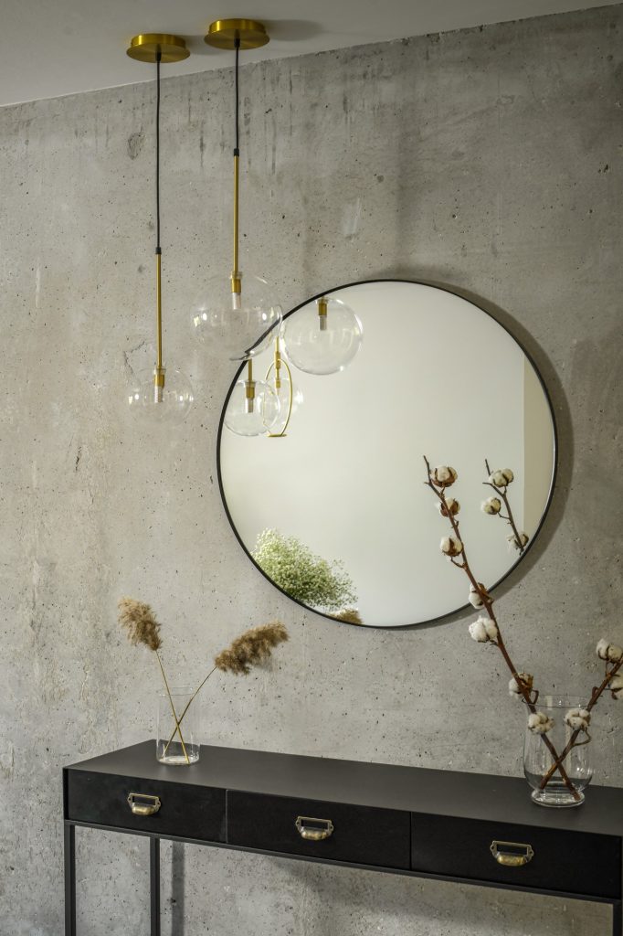 Round mirror above a black console