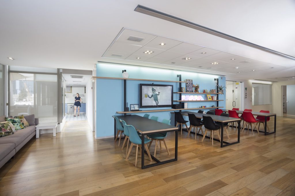 Shared desks facing a light blue wall and a screen